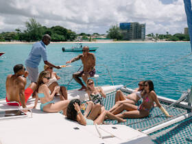 A lively group enjoys a day on a catamaran, sharing drinks and food while soaking up the sun — the perfect setting for a fun celebration on the water.