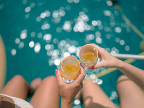 Two friends toast with cocktails while enjoying the sparkling turquoise waters — a perfect moment for relaxation and celebration on the water.