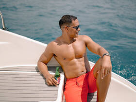 A man enjoys a refreshing drink while relaxing on the deck of a boat, capturing the essence of leisure on the open water.