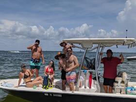 A lively group enjoys a fun day on the water, posing on their boat with drinks in hand — perfect for summer celebrations and memorable outings.