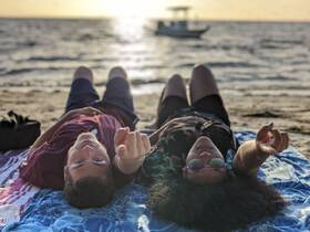 A couple enjoys a relaxing moment on the beach at sunset, capturing the essence of a perfect getaway with the ocean in the background.