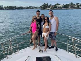 A lively group of friends poses on the bow of a boat, enjoying a beautiful day on the water — perfect for celebrations and memorable outings.