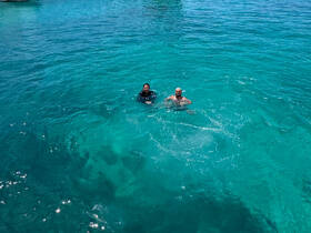 Two individuals enjoy a refreshing swim in crystal-clear waters, showcasing the perfect setting for aquatic adventures.