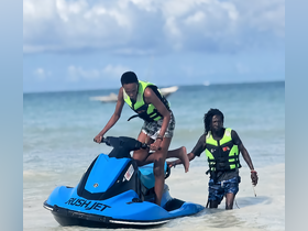 Two individuals enjoy a thrilling moment on a jet ski at the beach, showcasing the excitement of water sports and adventure.