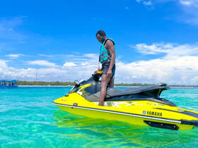 A person enjoys an exhilarating ride on a bright yellow jet ski in crystal-clear waters, perfect for adventure seekers looking to explore the coastline.