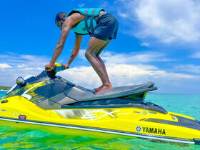 A rider enjoys an exhilarating moment on a jet ski, showcasing the thrill of water sports in a vibrant turquoise setting.