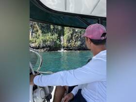 A man enjoys the stunning view of a waterfall while navigating a boat through crystal-clear waters, showcasing the beauty of nature during a boating adventure.