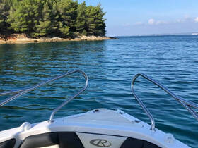A serene view from the front of a boat, showcasing clear waters and lush greenery along the shoreline — perfect for exploring tranquil coastal areas.