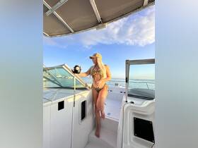 A woman enjoys a sunny day on a boat, holding a drink and soaking in the beautiful views — perfect for a relaxing day on the water.