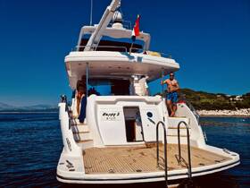 Two individuals enjoy a sunny day aboard the yacht 'Happy 3', showcasing a perfect summer getaway on the water.