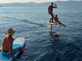 A thrilling moment on the water as a group enjoys paddleboarding and foiling, showcasing fun and adventure in the sun.