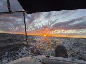 A stunning sunset view from the bow of a boat, showcasing the vibrant colors of the sky as the vessel navigates through the water — perfect for evening cruises.