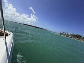 A scenic view from a boat cruising through turquoise waters, showcasing the beautiful coastline and vibrant sky — perfect for a day of exploration on the water.