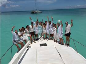 A lively group celebrates aboard a boat, enjoying the stunning turquoise waters — perfect for memorable gatherings and parties on the water.