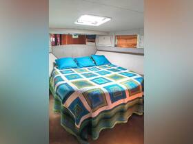Cozy interior cabin featuring a comfortable bed adorned with colorful bedding and cushions, perfect for relaxation on a boat.
