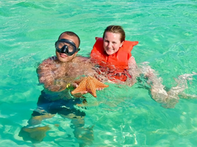 A joyful moment as two snorkelers interact with a starfish in the crystal-clear waters, showcasing a unique wildlife experience.