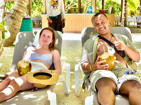 A couple enjoys a relaxing day at the beach, sipping fresh coconut drinks while lounging in the sun — a perfect getaway for beach lovers.