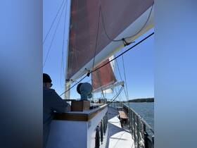 A view of the helm area on a sailing vessel, showcasing the intricate details of the boat's interior and the sails above, perfect for those interested in sailing experiences.