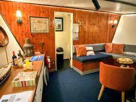 Cozy interior of a boat cabin featuring comfortable seating and decorative elements, perfect for relaxing during a voyage.