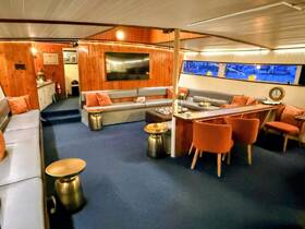 A cozy interior view of a boat's lounge area, featuring comfortable seating and a warm wooden ambiance, perfect for relaxing during a cruise.