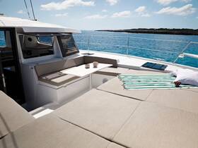 A beautifully designed lounge area inside a catamaran, featuring comfortable seating and a table, perfect for relaxing while enjoying the stunning ocean views.