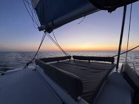 A serene view of a catamaran at sunset, showcasing the tranquil waters and vibrant sky — perfect for peaceful evening cruises.