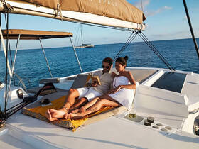 A couple enjoys a serene moment on the deck of a yacht, reading and relaxing together — an idyllic setting for romantic getaways or sunset cruises.