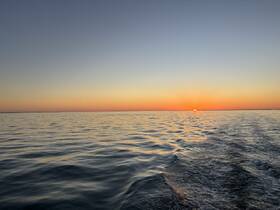 A serene sunset over calm waters, showcasing the beauty of nature during a peaceful boat ride.