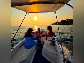A group enjoys a picturesque sunset on a boat, capturing the moment with smiles and laughter — a perfect family outing on the water.