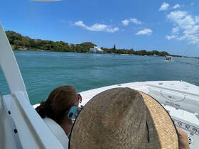 A woman enjoys a sunny day on the water, talking on her phone while cruising past lush greenery — a perfect moment for relaxation and exploration.