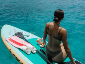 A woman enjoys paddleboarding in crystal-clear waters, showcasing the perfect blend of relaxation and adventure on the water.
