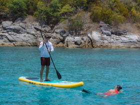 A paddleboarder enjoys the clear waters while a snorkeler explores beneath the surface, showcasing the perfect day for water activities in a tropical paradise.