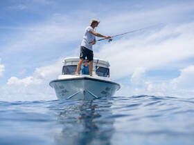 A fisherman casts his line from a boat in the open ocean, showcasing the thrill of fishing adventures on the water.