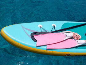 A vibrant paddleboard with pink snorkel fins resting on the crystal-clear waters, perfect for a day of aquatic adventures and exploration.