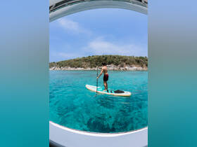 A man paddleboards in crystal-clear waters, surrounded by lush greenery — an ideal scene for water sports enthusiasts and adventure seekers.