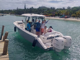 A lively group waves from aboard a boat, enjoying a fun day on the water with a beautiful beach backdrop — perfect for memorable outings and celebrations.