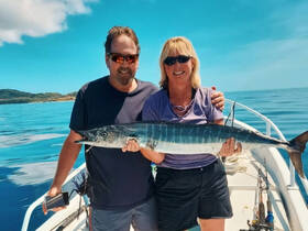 A couple proudly displays their impressive catch while fishing on a boat, showcasing the thrill of a successful day on the water.