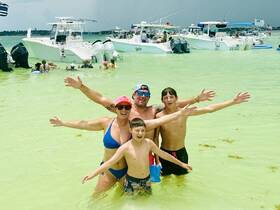 A joyful family enjoys a fun day at the beach, swimming in shallow waters surrounded by boats — perfect for creating lasting memories on a sunny day.