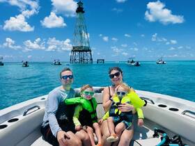 A joyful family enjoys a sunny day on a boat near a lighthouse, creating lasting memories on the water with kids in life jackets.