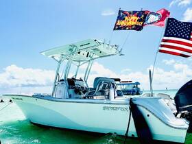 A stunning side view of a Sea Fox boat docked in clear waters, adorned with festive flags celebrating an anniversary — perfect for memorable outings on the water.