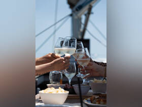 A group toasts with glasses of wine while enjoying snacks on a boat, capturing the essence of celebration and camaraderie on the water.