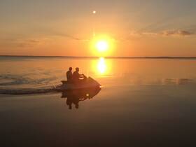 A couple enjoys a thrilling ride on a jet ski during a stunning sunset, capturing the essence of adventure on the water.