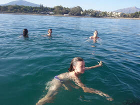 A joyful group enjoys swimming in clear waters, creating memorable moments under the sun — perfect for family outings or beach days.