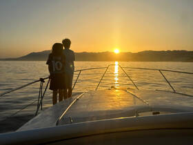 Two children enjoy a breathtaking sunset view from the bow of a boat, creating a perfect backdrop for memorable family moments on the water.
