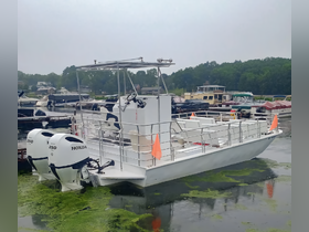 A center console boat docked in a marina, showcasing its sleek design and powerful Honda engines, surrounded by lush green water.