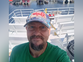 A man smiles for a selfie inside a boat, showcasing the seating area and helm in the background — perfect for capturing moments on the water.