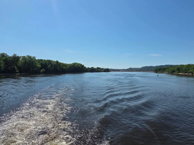 A serene view of a river landscape under a clear blue sky, showcasing the beauty of nature and perfect for a peaceful boating experience.