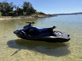 A sleek Sea-Doo jet ski rests on the clear waters, showcasing its design against a serene lakeside backdrop — perfect for thrilling water adventures.
