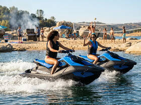 Two friends enjoy a thrilling ride on jet skis, showcasing the excitement of water sports at a beach gathering with friends.