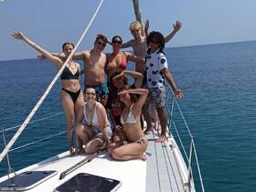 A lively group of friends poses on the deck of a sailboat, enjoying a sunny day at sea — perfect for memorable sailing adventures and celebrations.